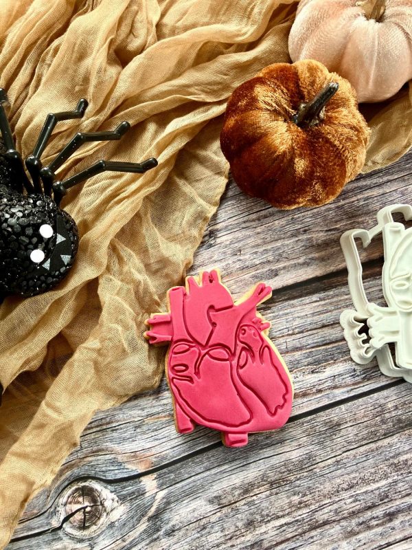 Human heart cookie cutter and fondant stamp with anatomical detail, displayed on a dark Halloween-themed surface, 3D-printed from biodegradable food-safe PLA