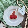 Red cherry cookie cutter and fondant embosser on white plate with green cloth