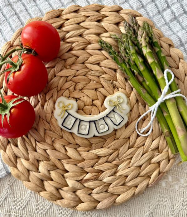 Bunting banner cookie cutter and fondant embosser set featuring birthday flags and pennant design displayed with tomatoes and asparagus on a woven placemat, 3D-printed from biodegradable food-safe PLA