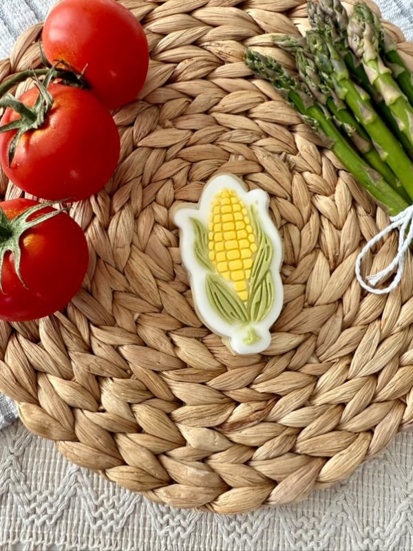 79E8D1BD-2625-4E2D-99D1-A1617BF7BFBD Corn cob cookie cutter and fondant embosser on woven mat with tomatoes