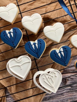 Miniature heart-shaped bride and groom cookie cutter and fondant stamp set, 3D-printed from biodegradable food-safe PLA, displayed on rustic wooden surface